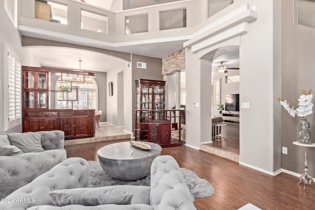 living room featuring dark hardwood / wood-style flooring, a towering ceiling, and ceiling fan