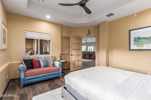 bedroom with wood finished floors, a raised ceiling, recessed lighting, a ceiling fan, and baseboards