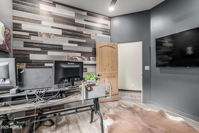 office area featuring an accent wall, wooden walls, and baseboards