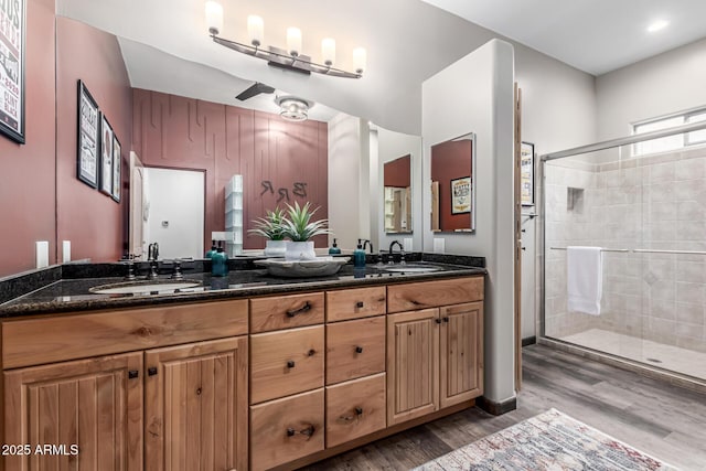 full bathroom with wood finished floors, a shower stall, and double vanity