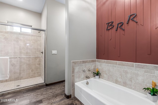 bathroom featuring a stall shower, a garden tub, and wood finished floors