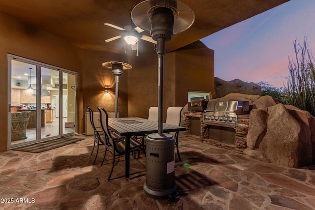 view of patio / terrace with an outdoor kitchen, area for grilling, a ceiling fan, and outdoor dining space