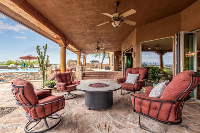 view of patio / terrace with a ceiling fan and an outdoor living space with a fire pit