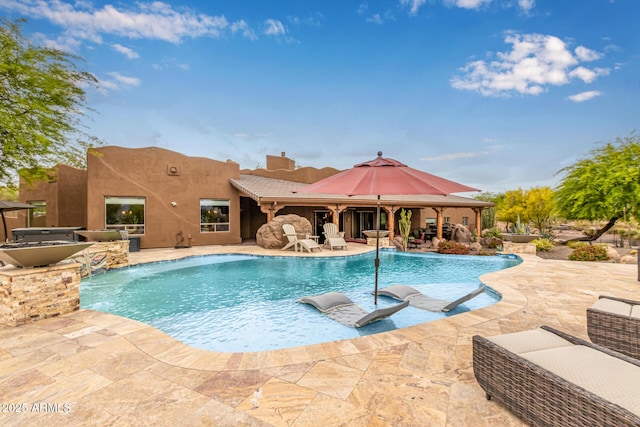 outdoor pool with area for grilling and a patio