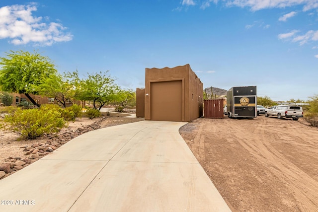 view of property exterior with concrete driveway, fence, and a gate