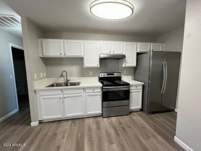 kitchen with a sink, white cabinetry, under cabinet range hood, and stainless steel appliances