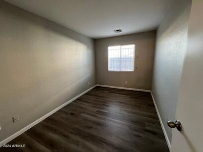 spare room with visible vents, baseboards, and dark wood-style flooring