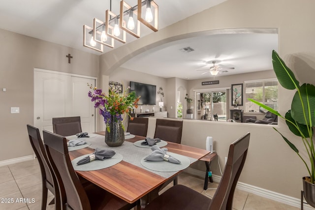 dining room with visible vents, baseboards, a ceiling fan, arched walkways, and light tile patterned floors