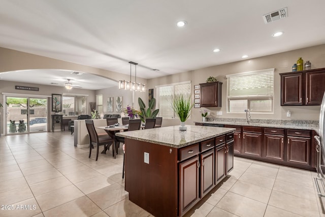 kitchen with a sink, open floor plan, visible vents, arched walkways, and recessed lighting