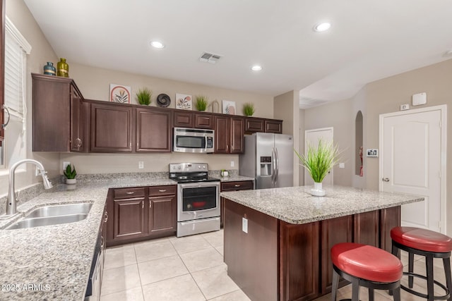 kitchen featuring visible vents, stainless steel appliances, a center island, a sink, and a kitchen breakfast bar