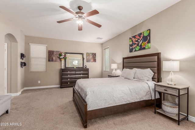 bedroom with arched walkways, baseboards, light colored carpet, and visible vents