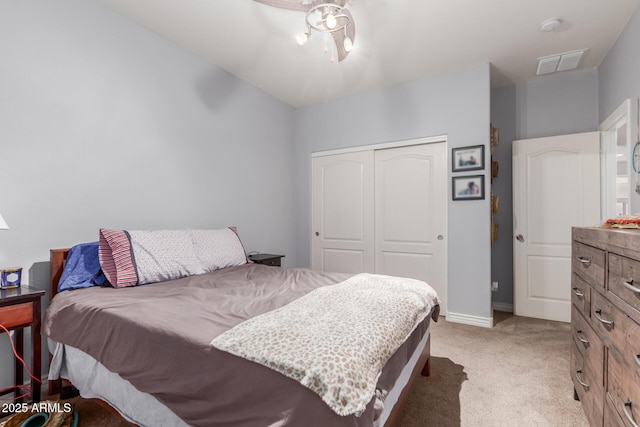 bedroom featuring baseboards, a closet, light colored carpet, and visible vents