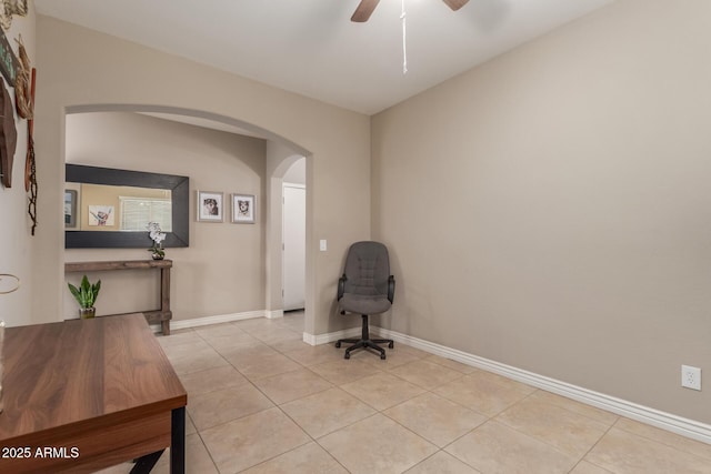 sitting room with arched walkways, a ceiling fan, baseboards, and light tile patterned flooring