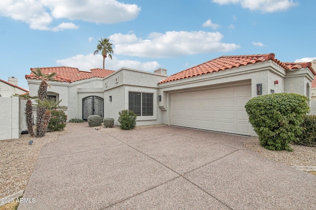 mediterranean / spanish house featuring a garage, concrete driveway, a tiled roof, and stucco siding