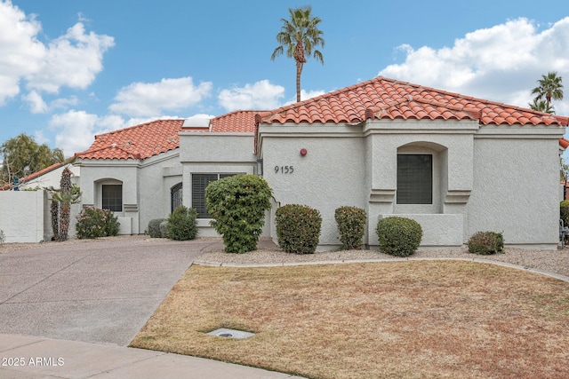 mediterranean / spanish house with a tiled roof, a front lawn, and stucco siding