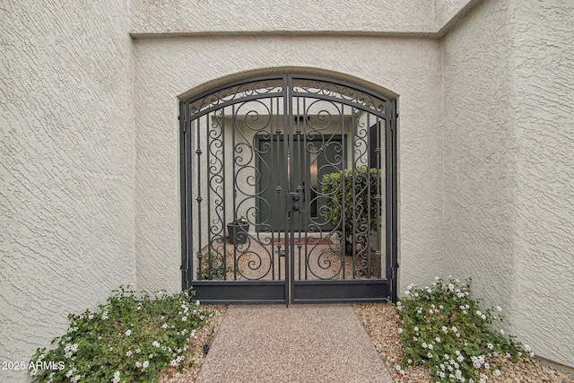 doorway to property featuring a gate and stucco siding