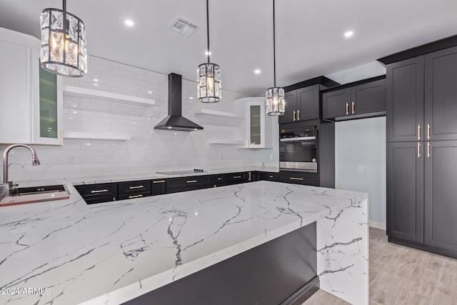 kitchen featuring decorative light fixtures, sink, stainless steel oven, and wall chimney exhaust hood