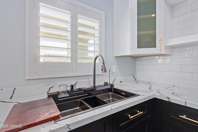 kitchen with sink, decorative backsplash, light stone countertops, and white cabinets