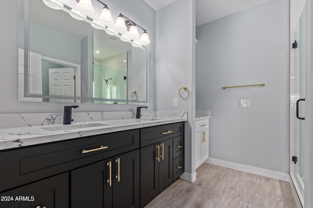 bathroom with wood-type flooring, a shower with shower door, and vanity