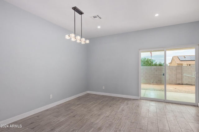 spare room with a chandelier and light hardwood / wood-style floors