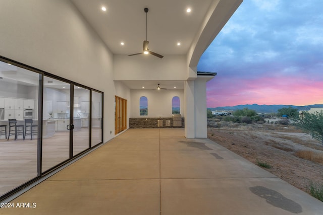 patio terrace at dusk featuring a mountain view and ceiling fan