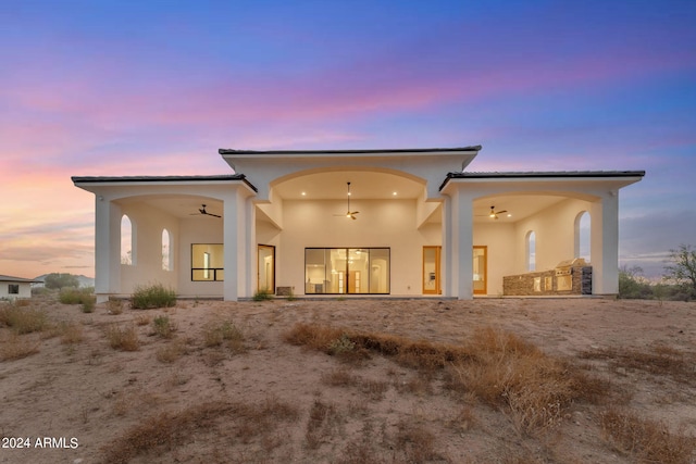 back house at dusk featuring ceiling fan