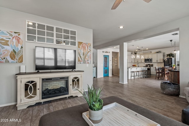 living room with dark hardwood / wood-style flooring, sink, plenty of natural light, and ceiling fan