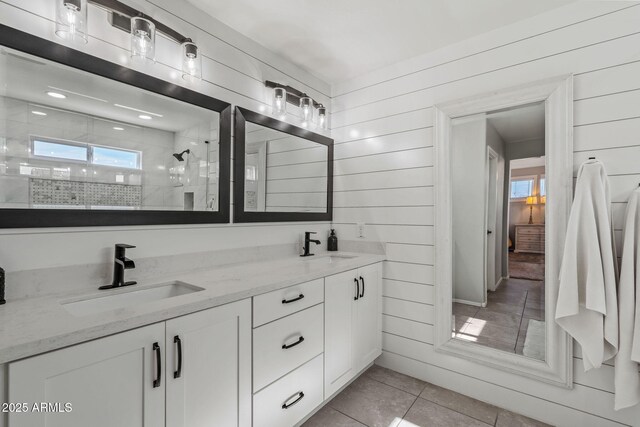 bathroom featuring plenty of natural light, vanity, wooden walls, and a tile shower