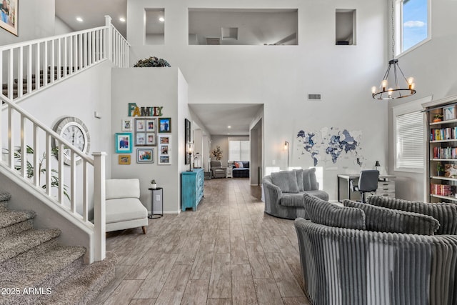 living room featuring a towering ceiling, hardwood / wood-style floors, and an inviting chandelier