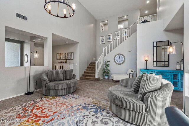 living room featuring hardwood / wood-style flooring, a towering ceiling, and a chandelier