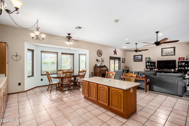 kitchen featuring light tile patterned floors, pendant lighting, ceiling fan with notable chandelier, and a center island