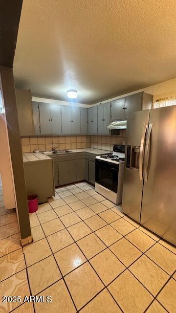 3530 W Portland St, Phoenix, AZ 85009 - kitchen featuring gas range gas stove, stainless steel refrigerator with ice dispenser, under cabinet range hood, gray cabinets, and a textured ceiling