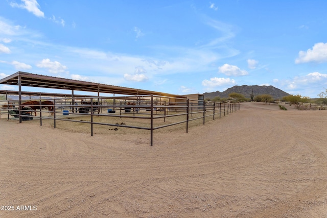 view of horse barn with a rural view and a mountain view