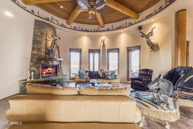 living room featuring wood ceiling, a stone fireplace, and a wealth of natural light