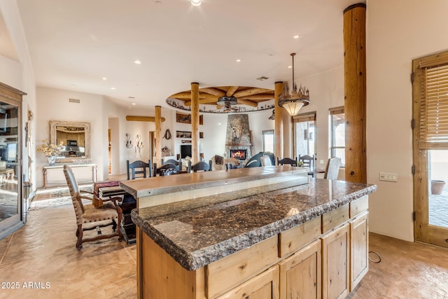 kitchen with hanging light fixtures, a center island, ceiling fan, and light brown cabinets