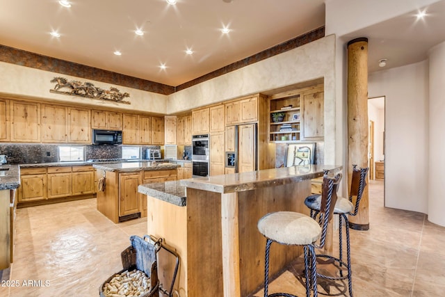 kitchen with decorative backsplash, a breakfast bar area, black appliances, and a center island