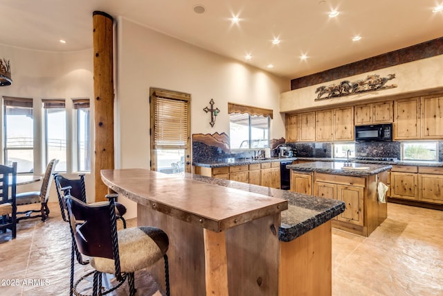 kitchen featuring tasteful backsplash, sink, a high ceiling, a center island, and black appliances