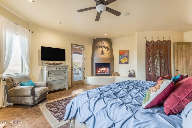 bedroom with ceiling fan, access to exterior, a large fireplace, and light tile patterned floors