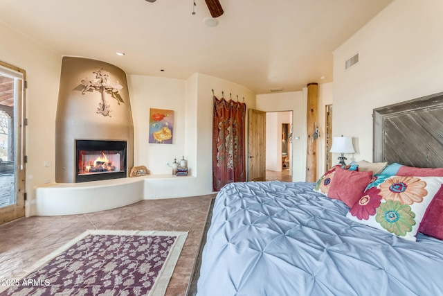 bedroom featuring ceiling fan, a fireplace, and tile patterned flooring