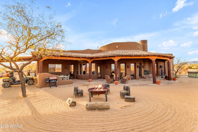 rear view of house with a patio and a fire pit