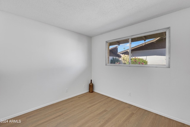 unfurnished room featuring a textured ceiling, baseboards, and light wood-style floors