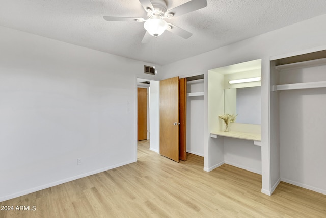 unfurnished bedroom with a textured ceiling, light wood-style floors, visible vents, and multiple closets