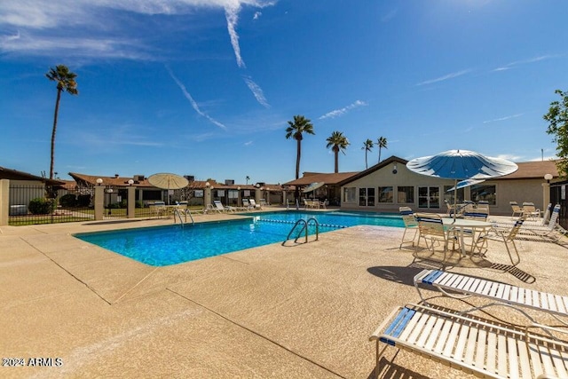 community pool with a patio and fence