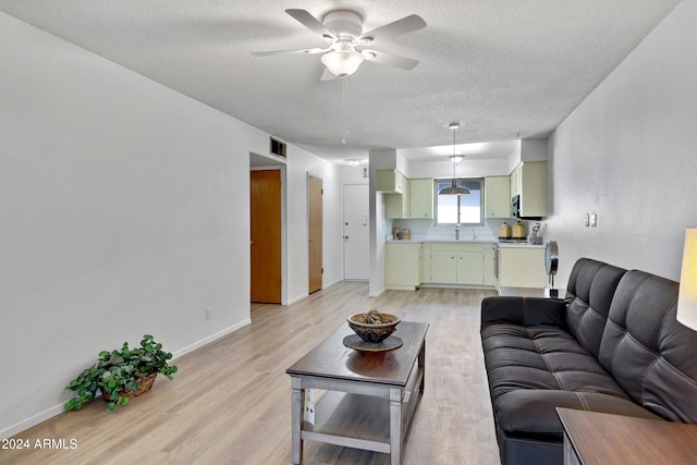 living room with light hardwood / wood-style flooring, a textured ceiling, and ceiling fan