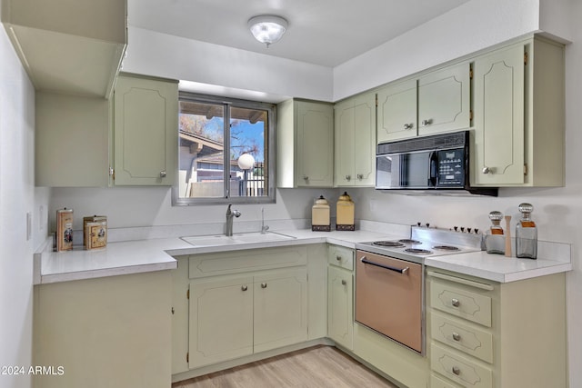 kitchen with light countertops, light wood-style floors, a sink, range with electric cooktop, and black microwave