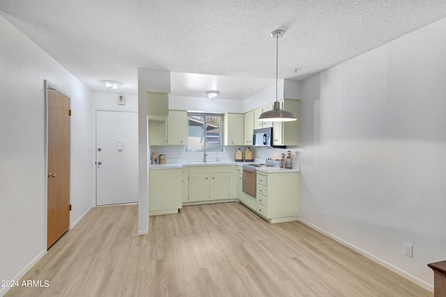 kitchen featuring decorative light fixtures, range with electric stovetop, light countertops, stainless steel microwave, and a sink