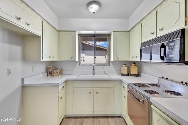 kitchen featuring electric stove, black microwave, light countertops, and a sink