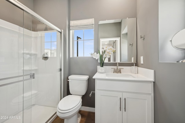 bathroom featuring a shower stall, toilet, vanity, and baseboards