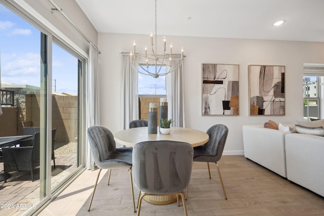 dining room with a wealth of natural light, baseboards, light wood-style floors, and an inviting chandelier