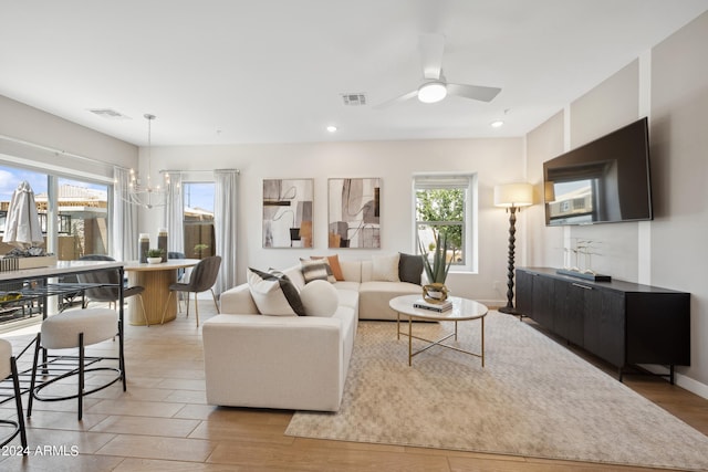 living room with visible vents, baseboards, light wood-style flooring, recessed lighting, and ceiling fan with notable chandelier